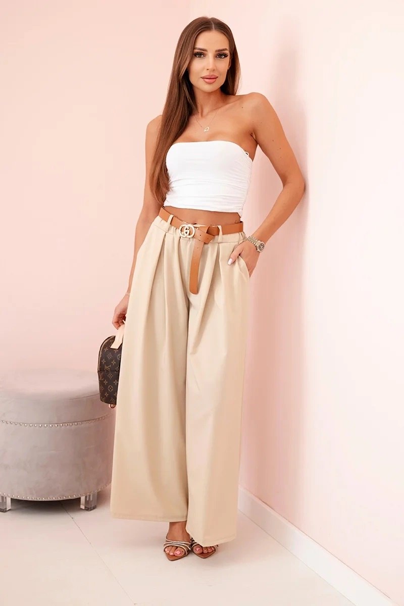 Styl oversize w modzie damskiej - stylizacja ze spodniami z paskiem i szeroką nogawką w kolorze jasno bezowym i białym topem damskim
